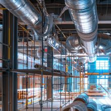 Construction site with installation of metallic air ducts and scaffolding in a commercial building. Concept of industrial infrastructure, HVAC systems, building construction.